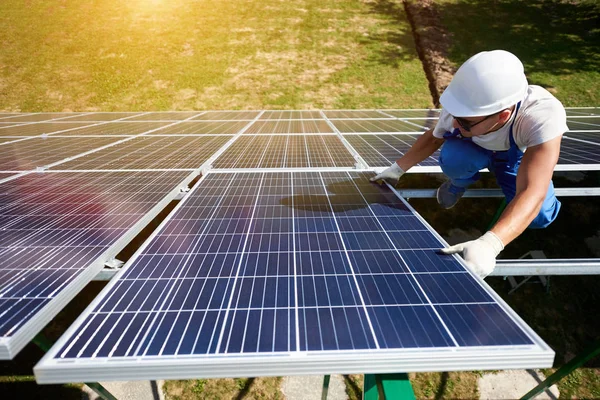 Yenilikçi güneş panelleri mavi üniforma ve koruyucu kask giyen genç bir işçi tarafından yükleme. Yenilikçi çözüm tasarrufu, yenilenebilir güneş enerjisini kullanarak elektrik için. Yüksek teknoloji dış.