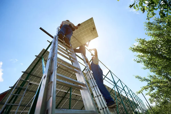 Equipe de montadores profissionais mantendo o painel de colar, instalando na carcaça . — Fotografia de Stock