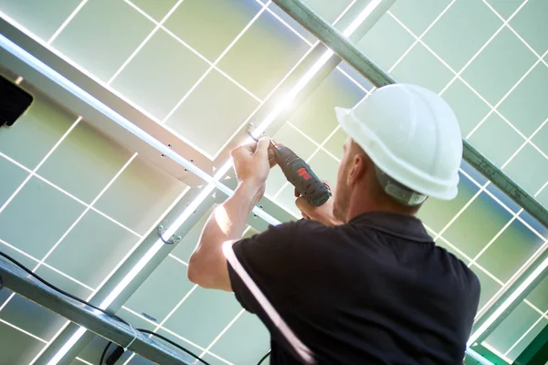 Mounter wearing white helmet working with drill installing solar panels. — Stock Photo, Image