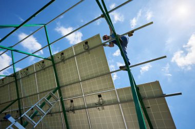 Profesyonel çalışan güneş panelleri üzerinde Metal Karkas yükleme. Güneş bataryaları üzerinde yeşil Metalik inşaat monte. Doğal koruma, yenilenebilir güneş enerjisi kullanarak kaynakları için modern çözüm.