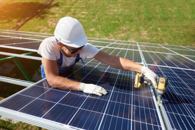 Farklı kullanýlýyor, miğfer profesyonel çalışan güneş panelleri yeşil metal konstrüksiyon üzerinde yükleme. Enerji çözümü için yenilikçi çözüm. Yenilenebilir kaynakları kullanın. Yeşil enerji.