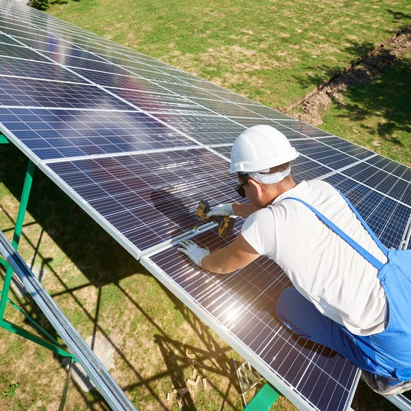 プロのマウンター緑金属枝肉に太陽電池をインストールします ドリルを使用して取付工事 天然資源の保存 再生可能な太陽エネルギーを使用して近代的なソリューションです ハイテク — ストック写真