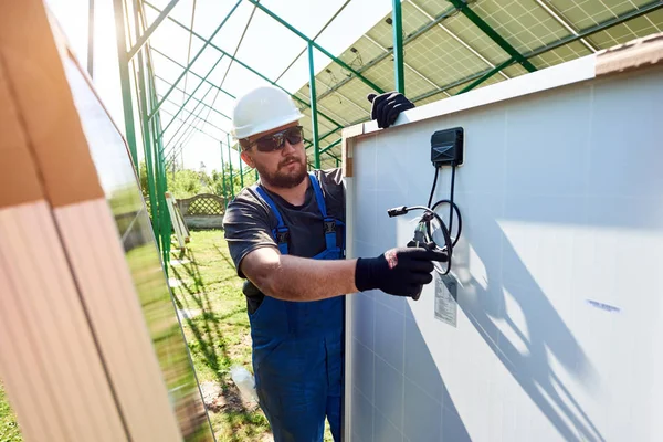 Worker cutting black pliers with special pliers, installing solar pannels on the green metal carcass. Innovative, environmental - friendly solution for energy solving, using renewable solar power