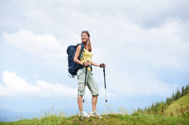 Sırt çantası, trekking, sopa yaz bulutlu gün zevk kullanarak giyen çimenli tepeye yürüyüş güzel mutlu kadın hiker dağ yolu, hiking. Açık hava etkinliği, turizm kavramı