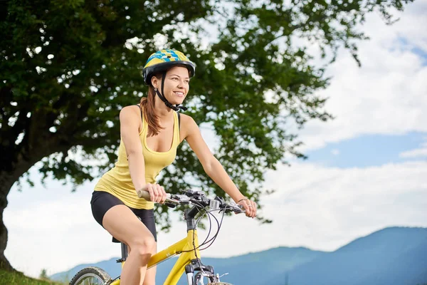 有魅力的快乐女子骑车骑着黄山的自行车在大树下 戴着头盔 在山上享受夏日的日子 户外运动活动 生活方式概念 — 图库照片