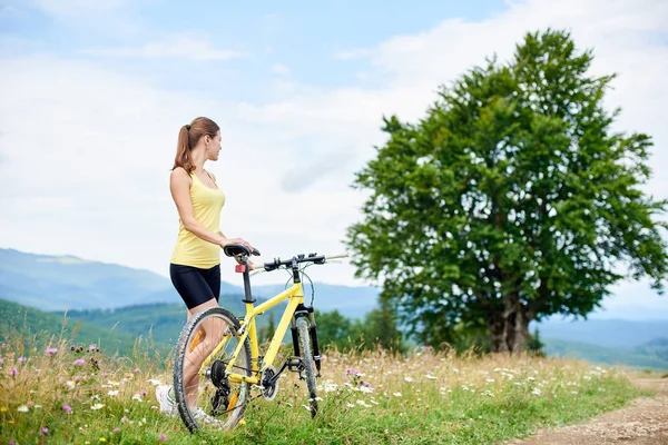 Sarı dağ bisiklet ile ayakta, dağlarda yaz günü zevk mutlu kadın motorcu. Açık spor aktivitesi, yaşam kavramı
