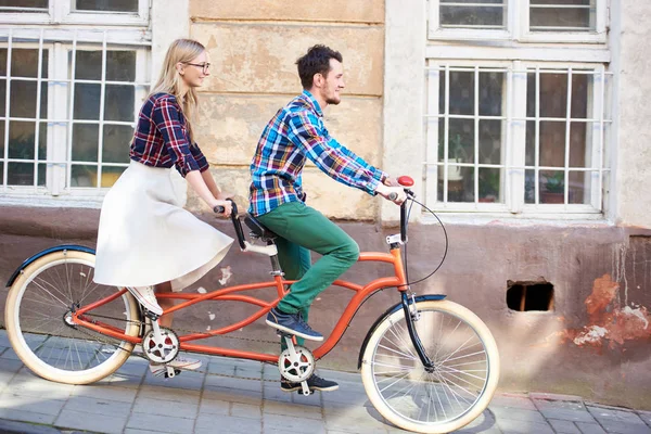 年轻浪漫的一对 英俊的男人和漂亮的金发女郎骑自行车一起在明亮的阳光明媚的夏日 沿着铺着双红色自行车的旧建筑 — 图库照片