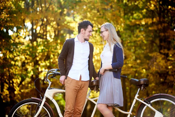活泼幸福浪漫的情侣 胡子男人和迷人的女人紧密在一起 在秋季公园或森林在阳光明媚的金色树木茂密的叶子背景的双联自行车户外 — 图库照片