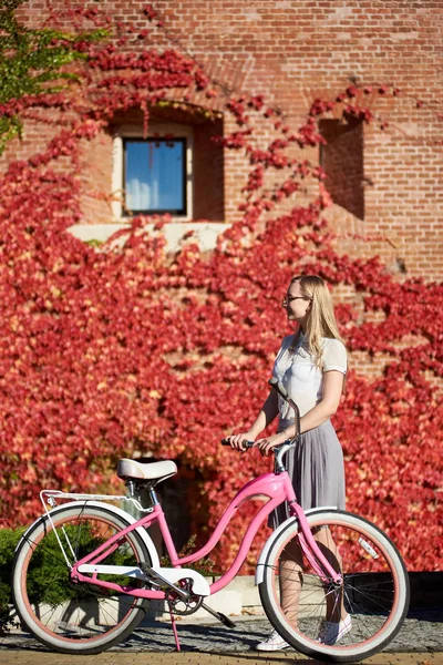 캐주얼 의류와 잎으로 배경에 따뜻한 화창한 레이디 자전거에서 포즈에서 — 스톡 사진