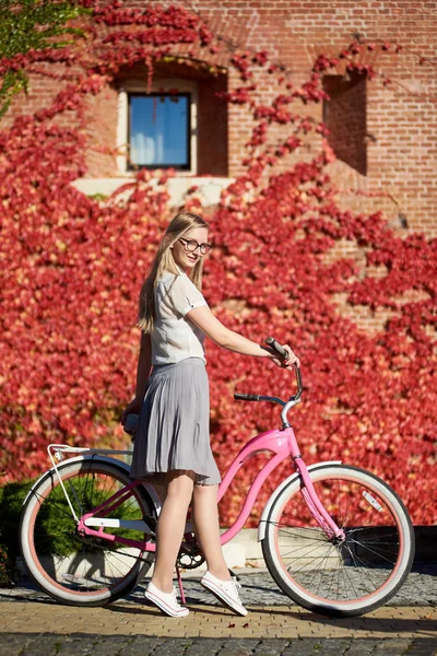 캐주얼 의류와 잎으로 배경에 따뜻한 화창한 레이디 자전거에서 매력적인 — 스톡 사진