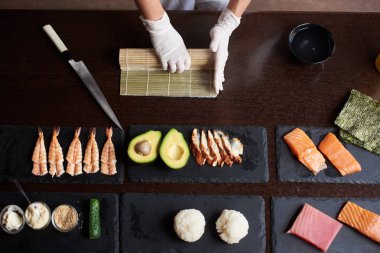 Usta bir suşi Nori ile rulo yapmak, mat pirinç, salatalık ve bambu kullanarak omlet. Pişirme işlemi Closeup görünümü. En baştan görüntülemek