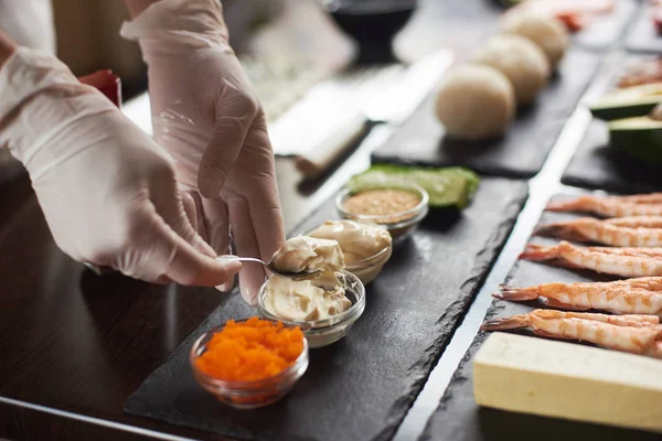 Closeup of chef hands preparing japanese food. Japanese chef making sushi rolls at restaurant.
