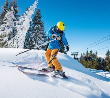Bir profesyonel freeride kayakçı kış Resort Karpatlar dağlarda güneşli bir günde sürme vurdu. Arka planda gökyüzü ve kış orman mavi