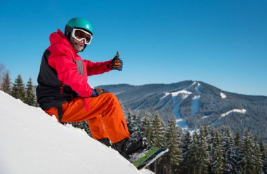 Erkek snowboard oturmuş, kış Kayak Merkezi, karlı yamaç rahatlatıcı portresi dağlarda, başparmak kadar kamera boşaltmak aşırı yaşam tarzı Hobi sporcu rekreasyon gösterilen