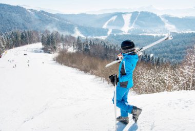 Tam uzunlukta omzuna yamaç onun kayaklar ile yürüyen bir kadın kayakçı bir kadeh. Kış Kayak Merkezi, ormanlar ve dağlar üzerinde arka plan boşaltmak