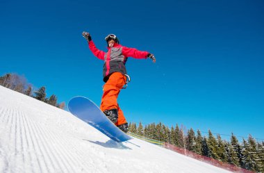 Dağ yamacında bir güzel güneşli kış gününde sürme sırasında havadaki snowboard. Mavi gökyüzü arka plan aktif yaşam tarzı spor kavramı üzerinde