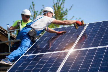 İki işçi teknisyenler ağır güneş Fotoğraf volta paneller yüksek çelik platforma yükleme. Dış güneş sistemi yükleme, alternatif yenilenebilir yeşil enerji üretimi kavramı.
