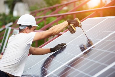 Profesyonel teknisyen tornavida metal platformu üzerinde sıcak güneşli yaz günü mavi parlak güneş Fotoğraf volta paneli bağlanma ile çalışma. Tek başına dış güneş paneli sistemi kurulması.