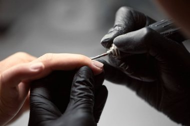 Profesyonel ana Şevval özçelik güzellik Close-up elektrikli matkap dosya istemci kadının tırnakları ile çalışan siyah eldiven eller. Parmak tırnak tedavisi, manikür yapma güzellik salonu.