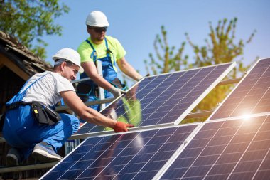 İki profesyonel teknisyen ağır güneş Fotoğraf volta paneller yüksek çelik platforma yükleme. Dış güneş sistemi yükleme, alternatif yenilenebilir yeşil enerji üretimi kavramı.