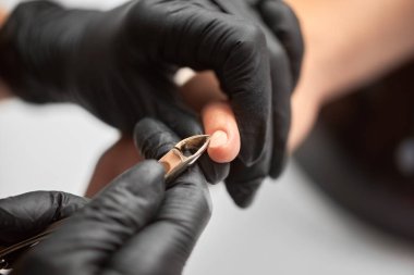 Ana Şevval özçelik güzellik Close-up kütikül istemci tırnak Tırnak makasları ile kaldırma siyah eldiven eller. Tırnakları tedavi, profesyonel araçlar, manikür yapma güzellik salonu konsept.