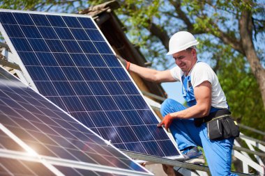Profesyonel teknisyen yüksek metal platforma mavi gökyüzü ve yeşil ağaç arka plan ağır güneş Fotoğraf volta panelini takma. Tek başına güneş sistemi yükleme, yeşil enerji üretim kavramı.