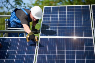 Profesyonel teknisyen tornavida kullanarak metal platforma güneş paneli bağlayan merdiven üzerinde duruyor. Dış güneş sistemi yükleme, yenilenebilir yeşil enerji üretimi kavramı.
