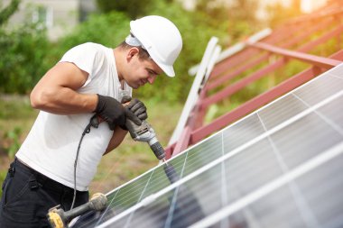 Mavi parlak güneş Fotoğraf volta paneli metal platformu sıcak yaz gününde Elektrikli tornavida kullanarak bağlanma teknisyen görünümünü profil. Tek başına güneş paneli sistemi yükleme konsepti.