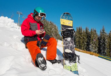 Kayak Merkezi, kara oturan snowboard dağlar teknoloji iletişim taşıyıcı hareketlilik rekreasyon spor yaşam tarzı içinde dinlenme sırasında akıllı telefonunu kullanarak