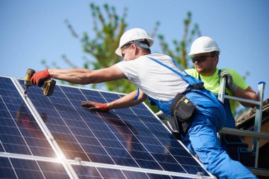 İki işçi teknisyenler ağır güneş Fotoğraf volta paneller yüksek çelik platforma bağlanma. Dış güneş sistemi yükleme, alternatif yenilenebilir yeşil enerji üretimi kavramı.
