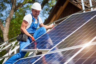 Profesyonel teknisyen yüksek metal platformu üzerinde mavi gökyüzü ve yeşil ağaç arka plan ağır güneş Fotoğraf volta paneline ayarlama. Tek başına güneş sistemi yükleme, yeşil enerji üretim kavramı.