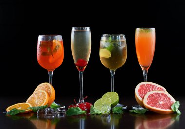 Dört farklı ile kompozisyon kristal kokteyl bardağı soğuk içecekler, portakal, limon ve greyfurt dilim, eriyen buz, nane yaprakları ve siyah arka plan üzerinde kırmızı kiraz şekillendirir. Oranı 1:1