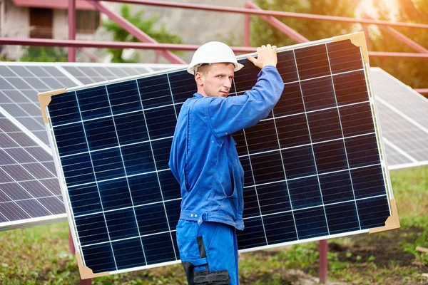 Jovem Trabalhador Uniforme Azul Capacete Proteção Transportando Grande Painel Solar — Fotografia de Stock