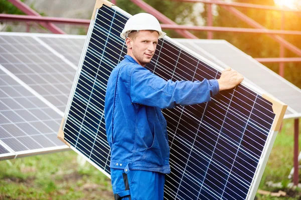 Jovem Trabalhador Uniforme Azul Capacete Proteção Transportando Grande Painel Solar — Fotografia de Stock