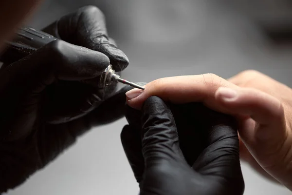 专业高手指甲手用黑色手套工作 在客户女性指甲上使用电钻文件 指甲治疗 美容美发制作 — 图库照片