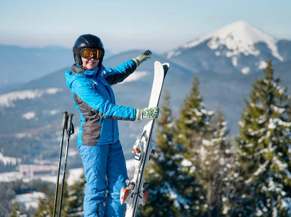 拍摄的一个微笑的女人滑雪 站在山滑雪胜地 指着令人惊叹的冬季天然景观围绕她 Copyspace 享受幸福康乐的季节性体育 — 图库照片