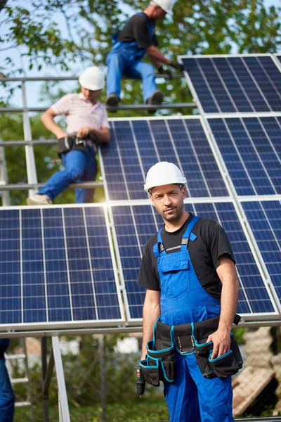 未完成の高外観ソーラー パネル太陽光発電システムのブルーの光沢のある表面前の電気ドライバーの地位を持つエンジニア技術者の高いプラットフォームの労働者のチームと肖像画 — ストック写真