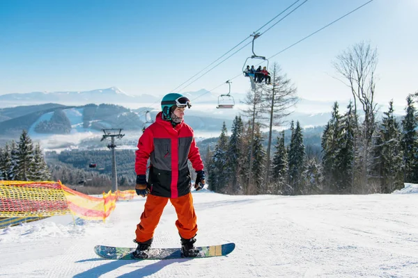 男人站在他的滑雪板滑雪升降机可见背后的背景蓝色天空与冬季度假胜地滑雪坡上阳光灿烂的日子 在早上 滑雪季节和冬季运动的概念 Bukovel 乌克兰 — 图库照片