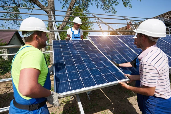 Equipo Tres Jóvenes Técnicos Cascos Protectores Que Ajustan Paneles Fotovoltaicos — Foto de Stock