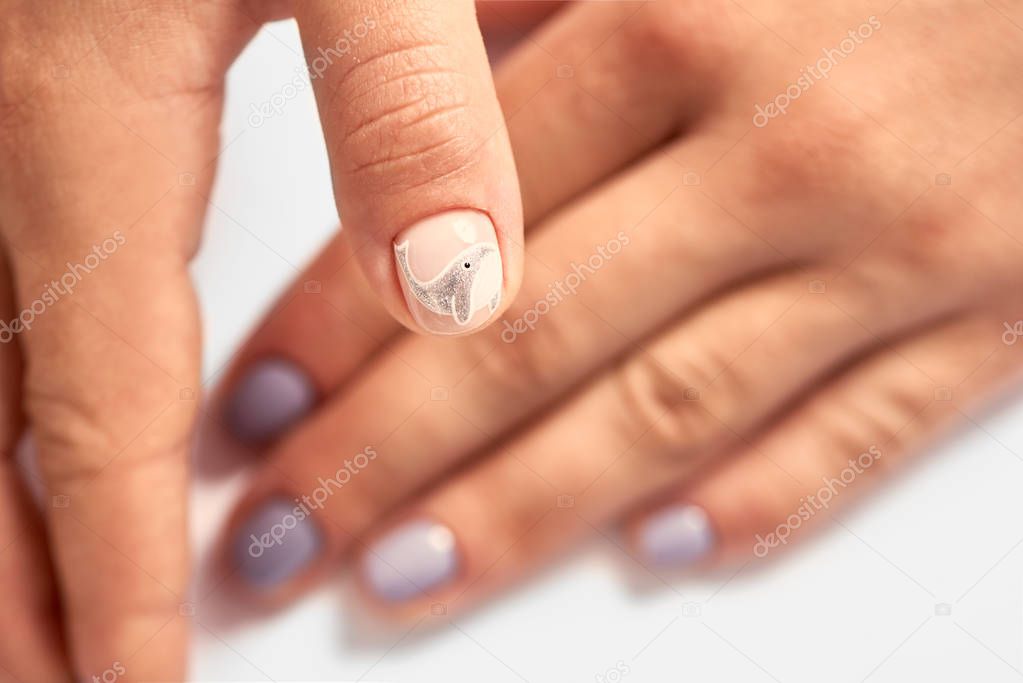 Close-up of professional manicurist hands painted elegant abstract silver glitter design on client woman painted nails in beauty salon. Beauty and fashion concept.