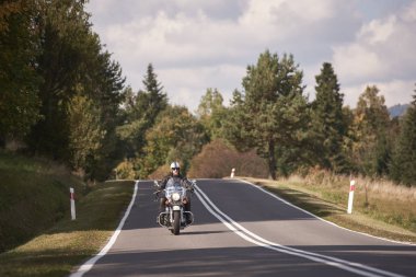 Siyah deri bir kıyafet binme Kruvazör Bisiklet parlak güneşli yaz gününde güzel yol boyunca yakışıklı motosikletçi