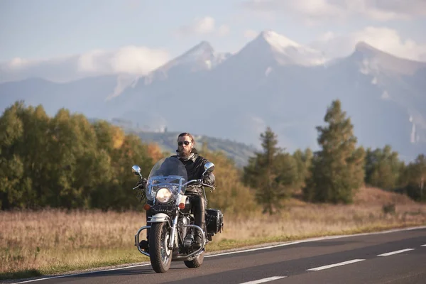 サングラスと白い雪に覆われた峰 と明るい夏空コピー スペース背景青霧山脈現代の強力な高速のバイクに乗って黒革衣類のひげを生やしたモーターサイク リスト — ストック写真