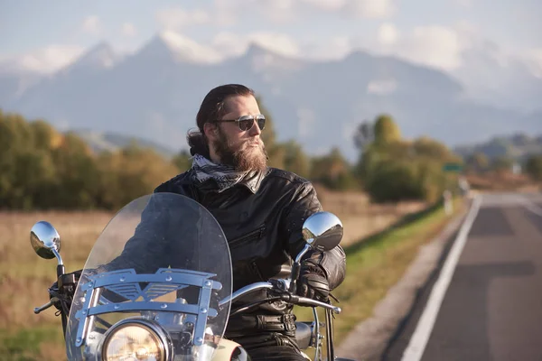 緑の風景 遠く白山 明るい青空の背景をぼかしの国沿道にバイクのハンドルを保持している黒い革のジャケットでハンサムなひげを生やしたバイカーの肖像画 — ストック写真
