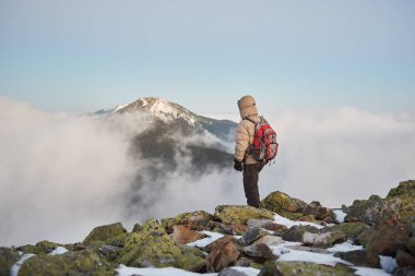 Vadinin arka plan üzerinde kayalık karlı dağ tepe üzerinde sırt çantası ile turizm uzun yürüyüşe çıkan kimse 