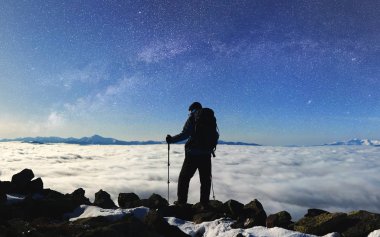 Dağın tepesinde büyük kayalar üzerinde duran uzun yürüyüşe çıkan kimse turist adam sırt çantası ve uzun yürüyüşe çıkan kimse sopa
