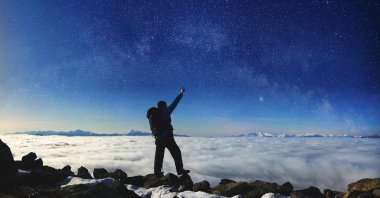 Büyük kayaların üzerinde duran ve üzerinde mavi gökyüzü işaret sırt çantası ve trekking Polonyalılar ile turizm uzun yürüyüşe çıkan kimse 