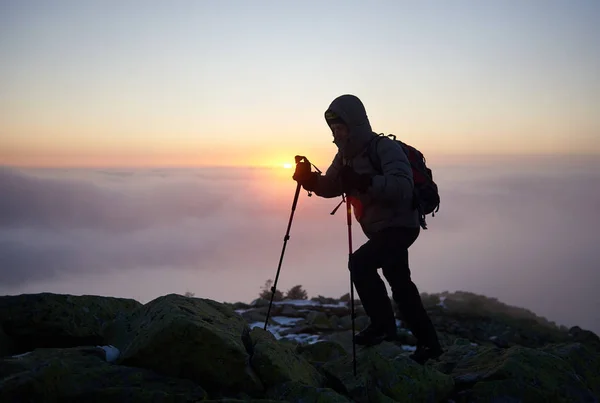 Силуэт Туриста Рюкзаком Альпинистскими Палками Скалистой Вершине Горы Туманными Облаками — стоковое фото