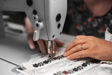 Modern dikiş makinesi üzerinde çalışan ve çiçek renkli Nakış Dantel Uzun çizgili beyaz kumaş Ayrıntılar bağlanmasını kadın terzi el yakın çekim