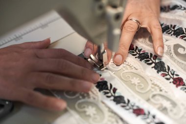 Modern dikiş makinesi üzerinde çalışan ve çiçek renkli Nakış Dantel Uzun çizgili beyaz kumaş Ayrıntılar bağlanmasını kadın terzi el yakın çekim