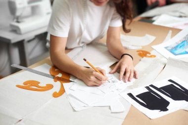 İş yerinde tasarım stüdyosu, profesyonel kadın tasarımcı kağıt desenleri ölçüm kaset, cetvel ve eğrileri kullanarak yapma